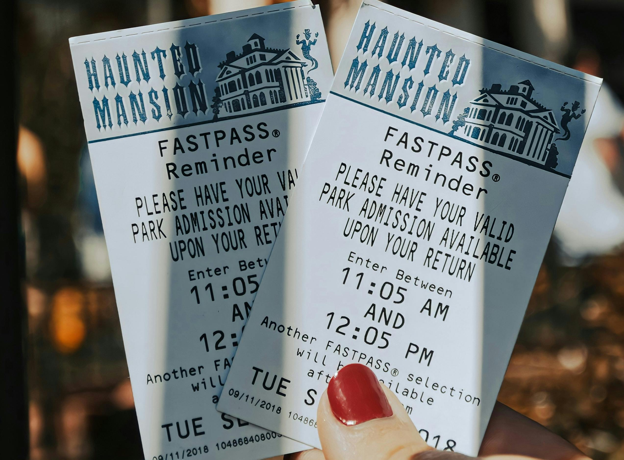 hand holding two tickets to a haunted mansion