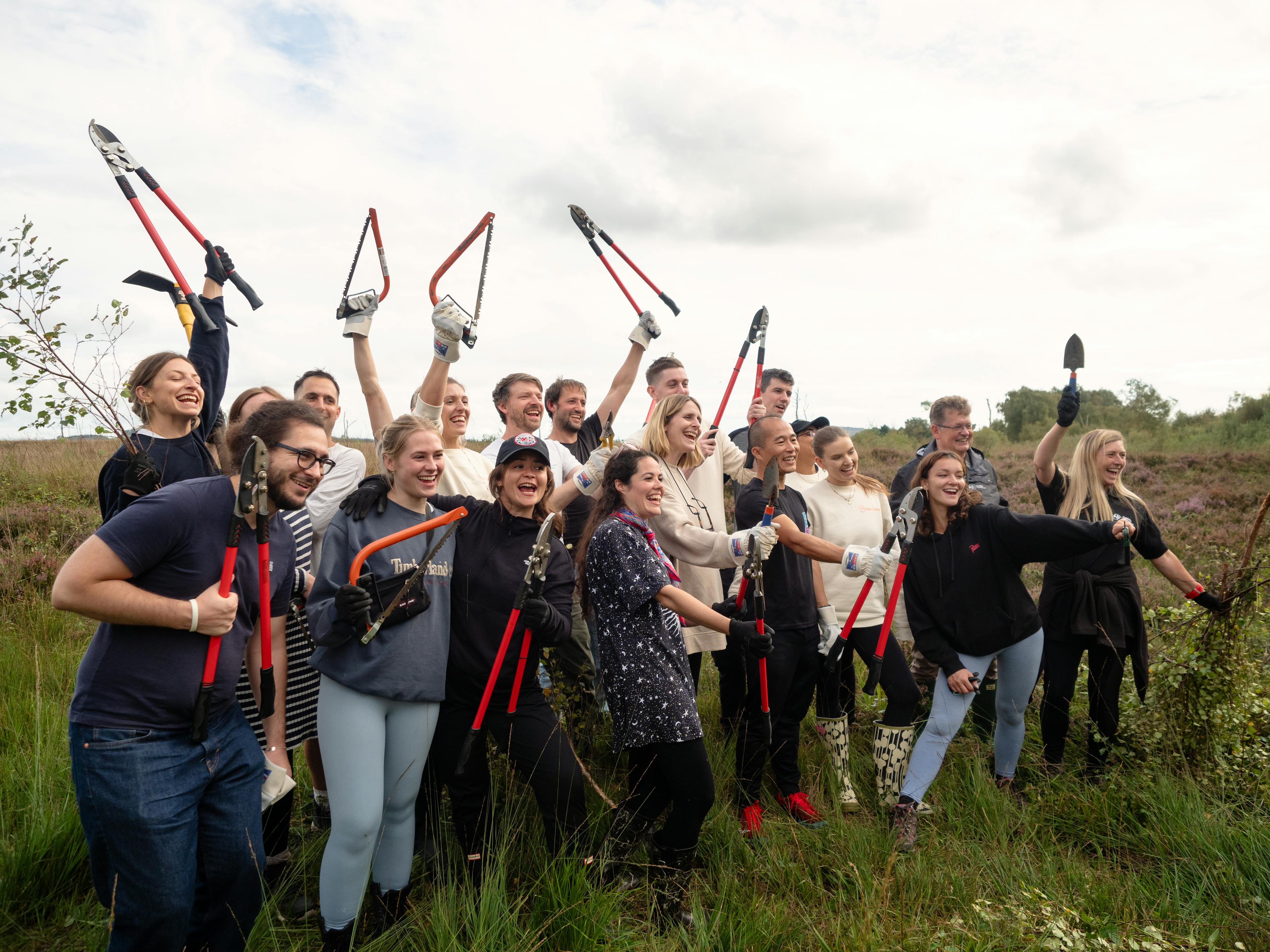 The Ticket Tailor team in a field with tools carrying out work for Cumbria Wildlife Trust
