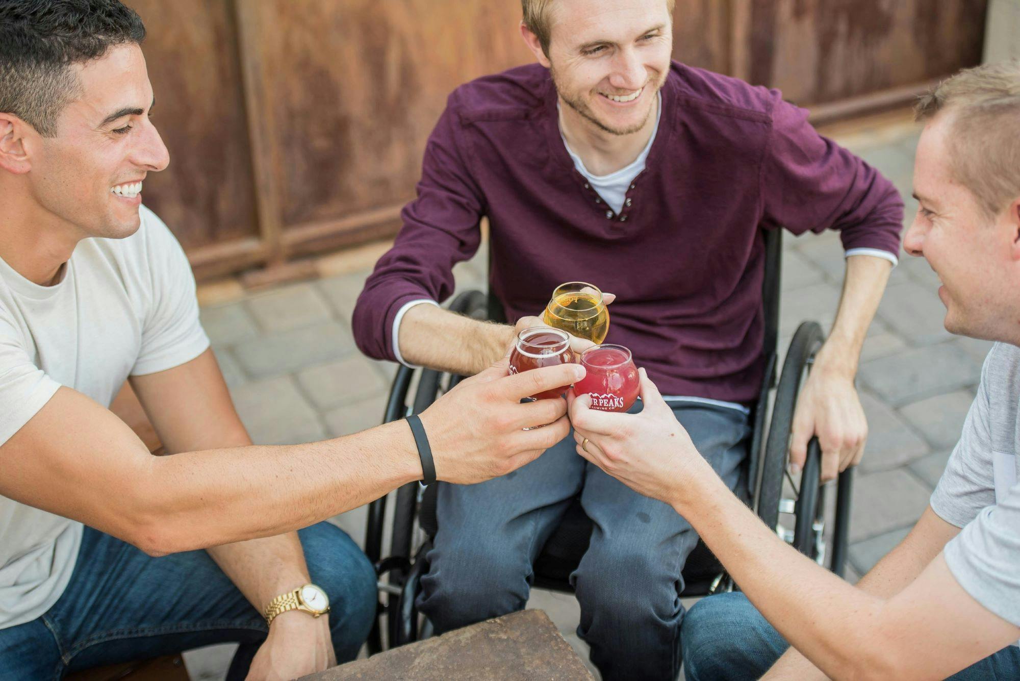 Three men in wheelchairs drinking