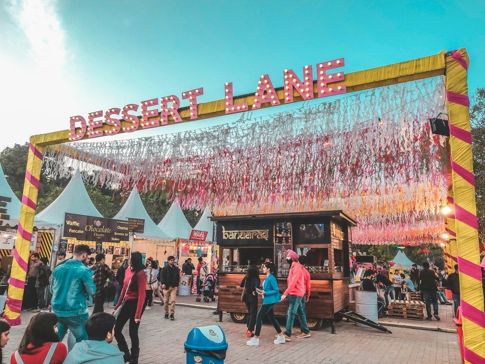 People in food festival with big sign saying dessert lane