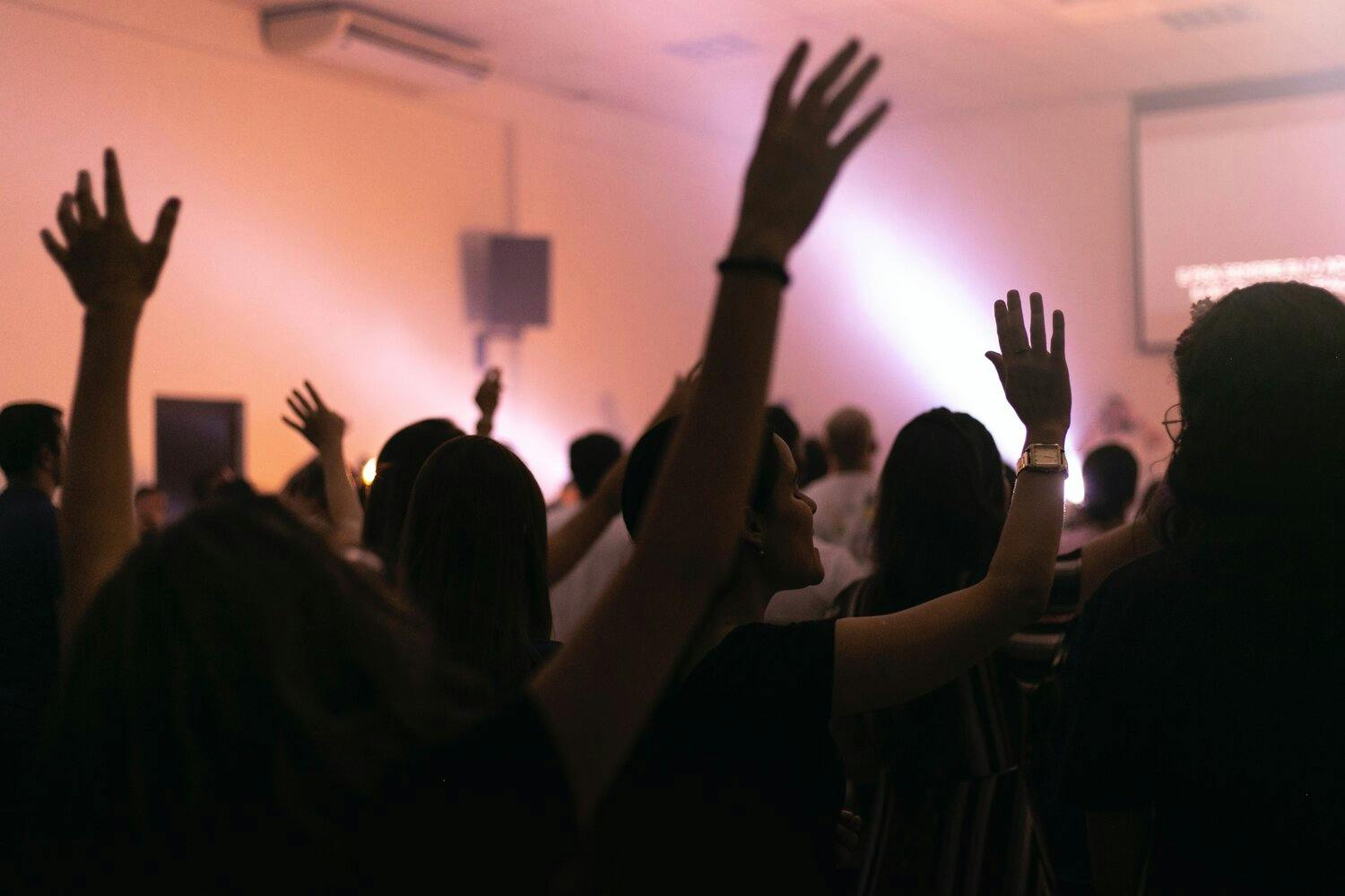 a group of people raising their hands in a room
