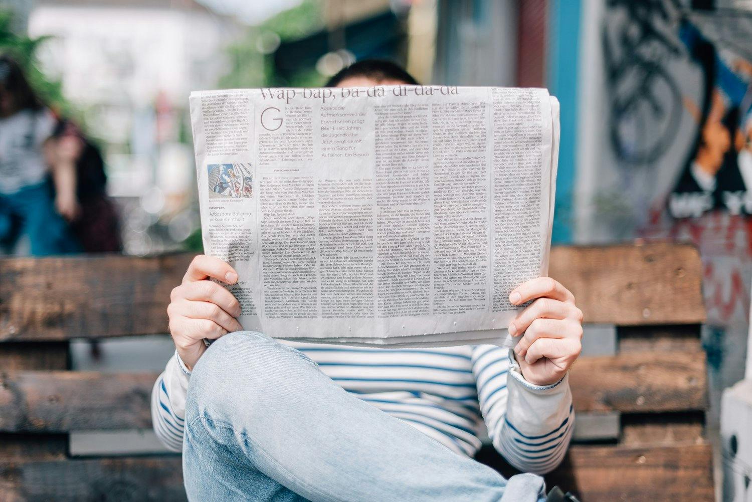 a person sitting on a bench holding a newspaper