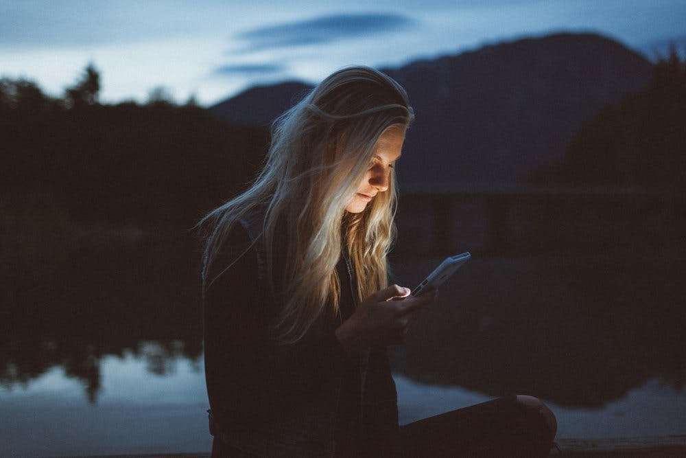 a person sitting on a dock looking at her phone