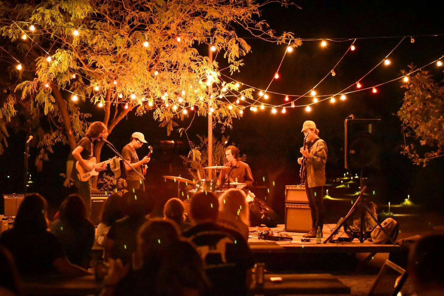 a group of people playing instruments on a stage with lights