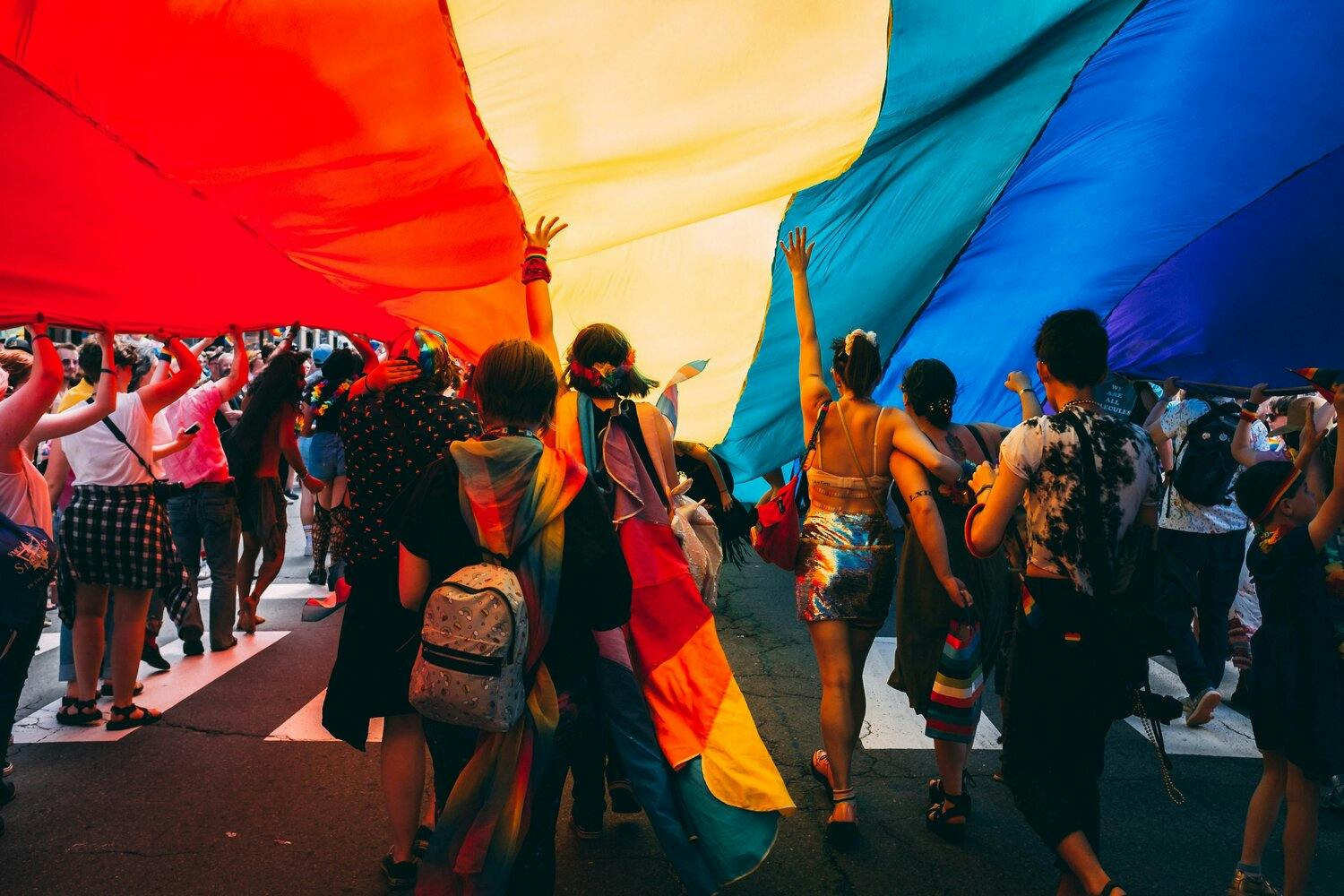 a group of people holding a large rainbow flag