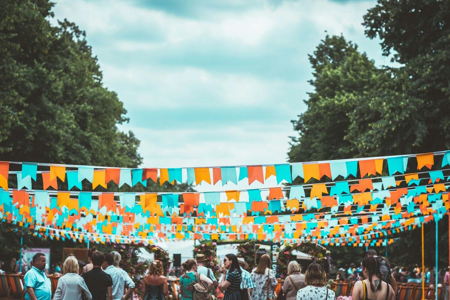 a group of people walking under a string of flags