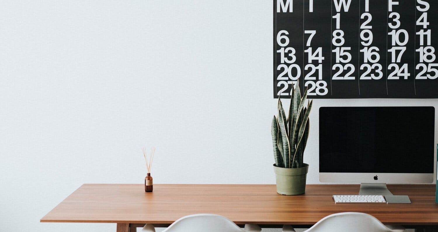 a desk with a potted plant and a computer