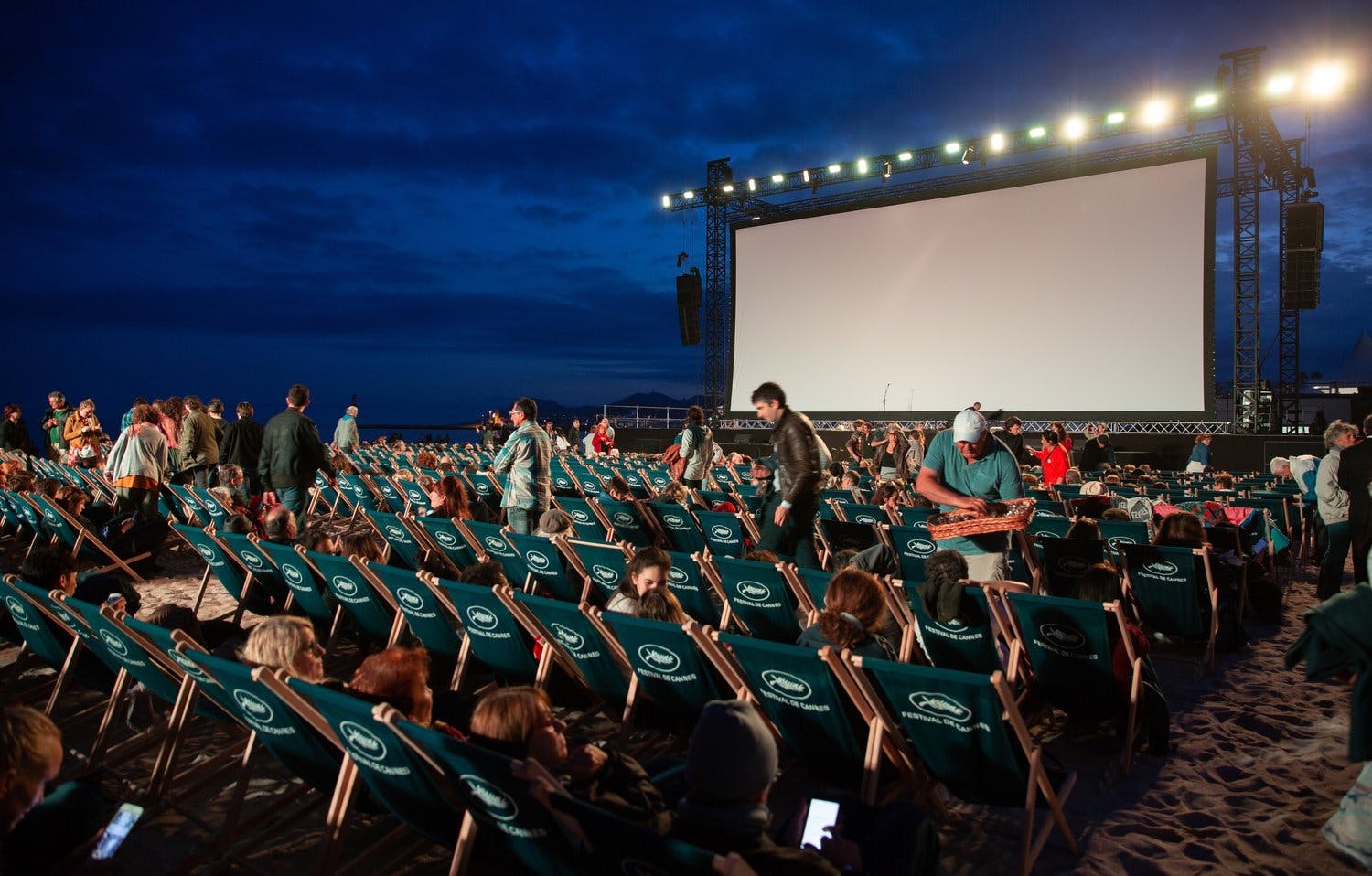 a group of people sitting in chairs in front of a large screen