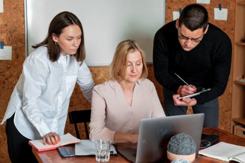 a group of people looking at a laptop