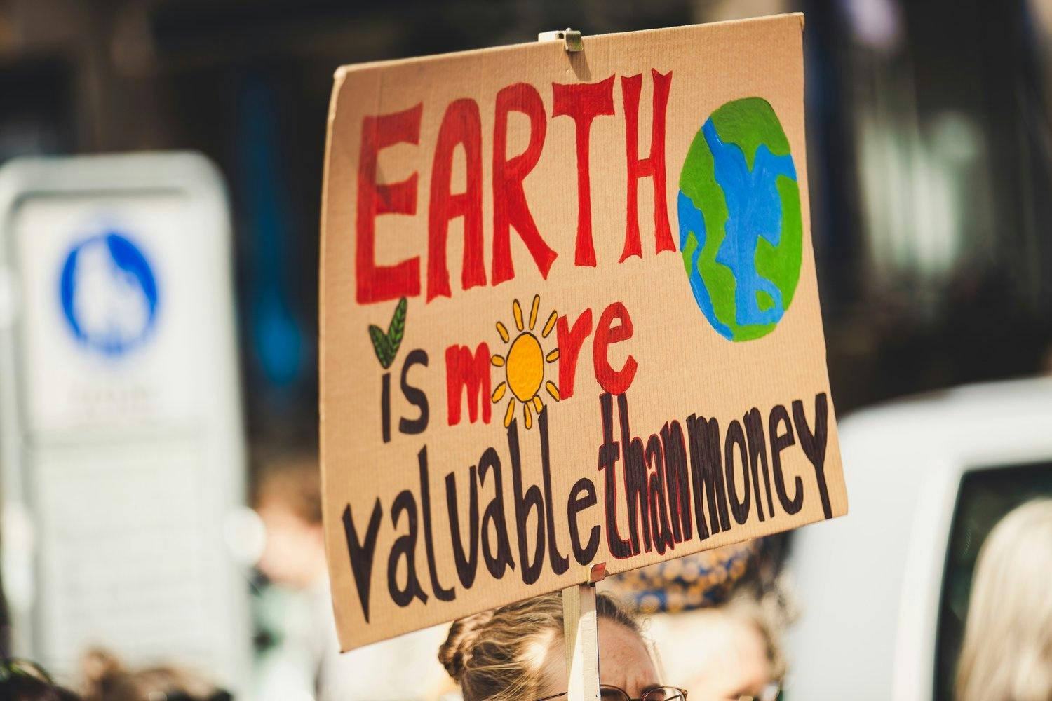 a person holding a sign earth is more valuable than money