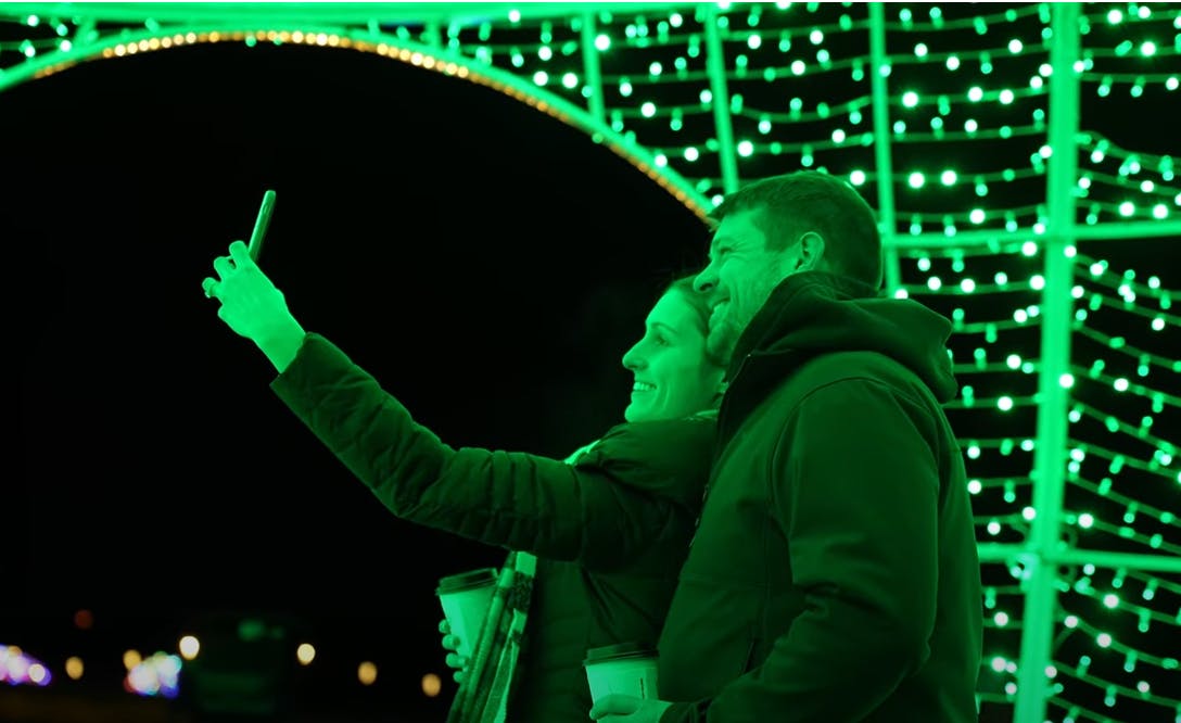 LaBelle Lights couple taking selfie under green light arch