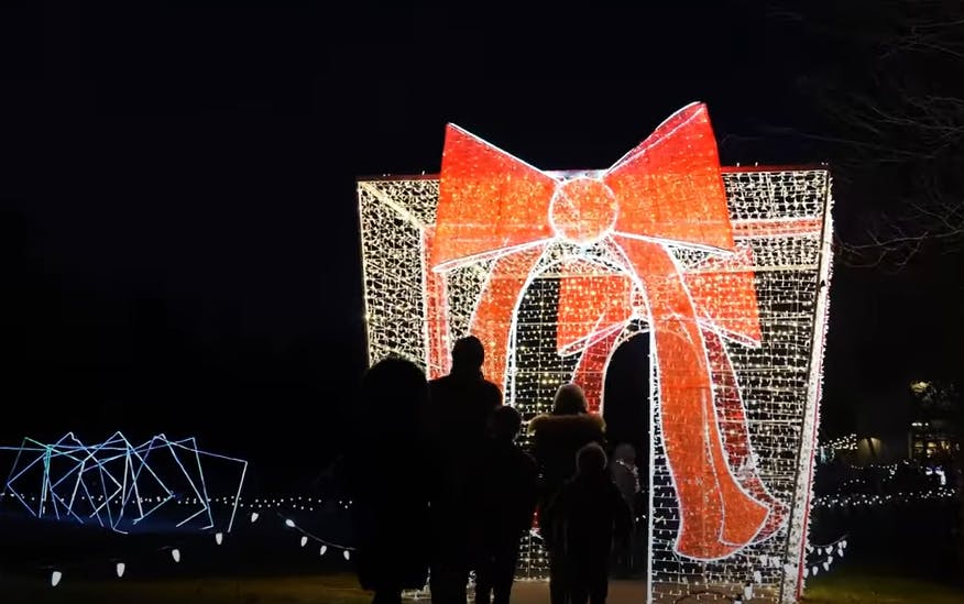 LaBelle Lights big light structure with red bow and people walking beneath