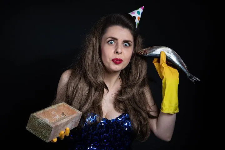 a person wearing a party hat and holding a fish in her hand