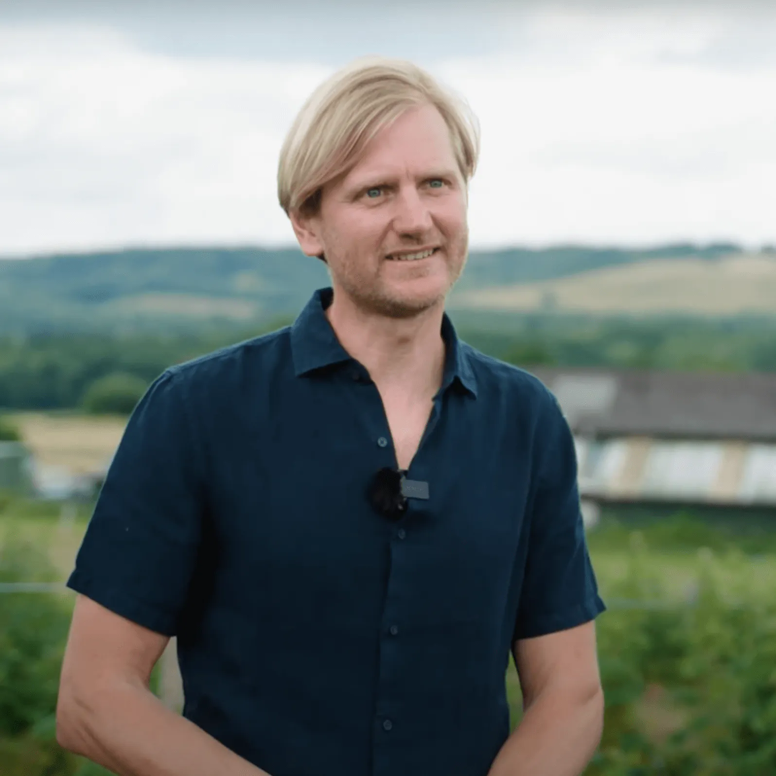a man smiling with the farm in the background