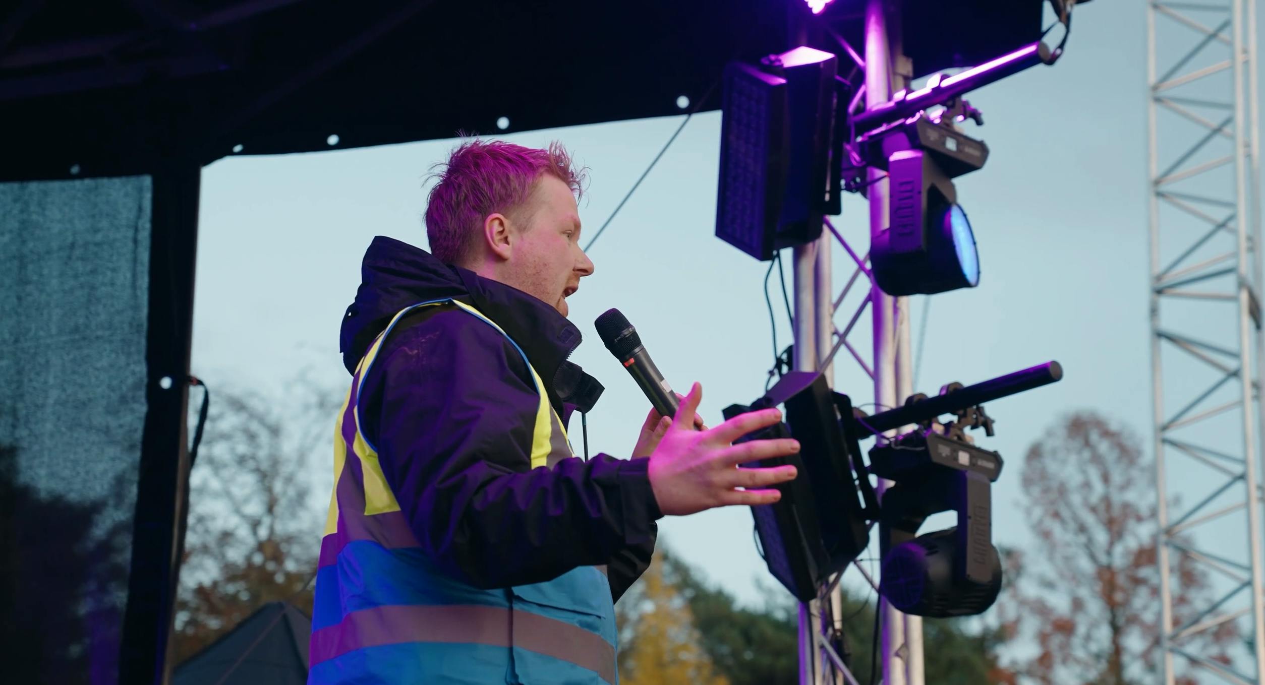 Kyle briefing the team on stage with a microphone