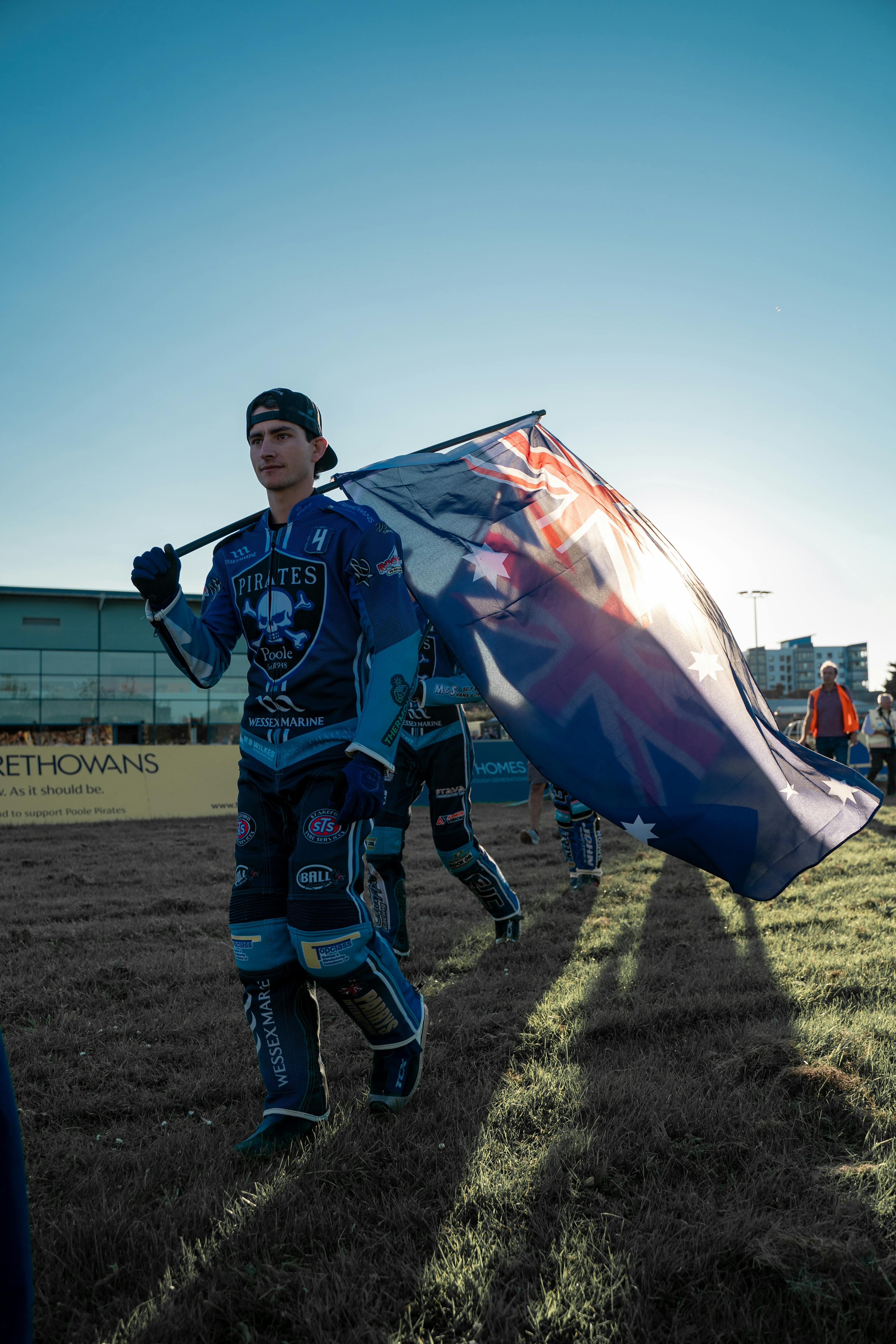 Person walking waving large flag at poole speedway