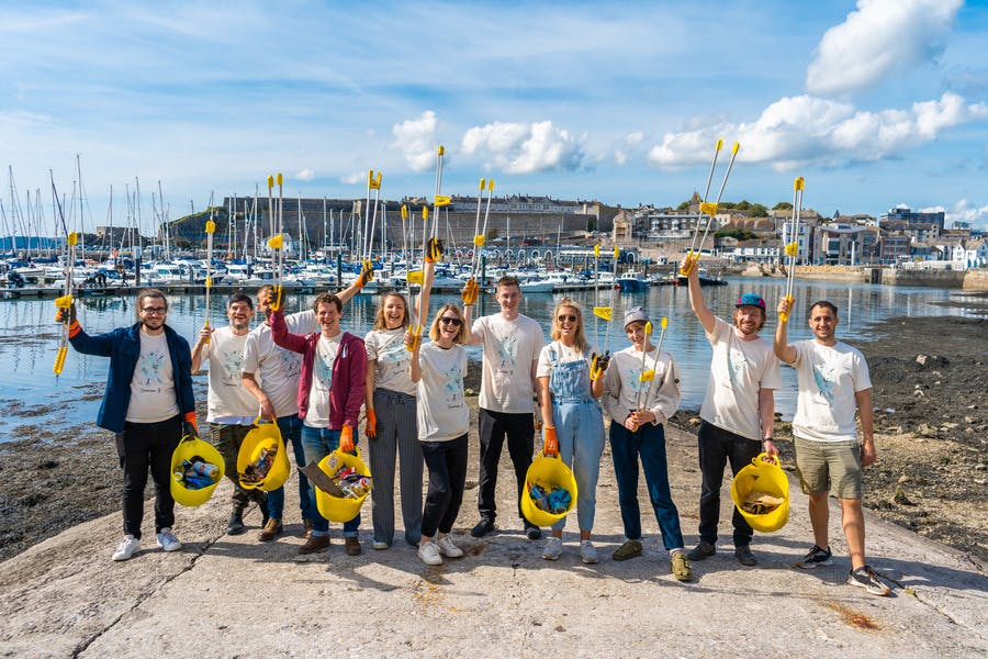 Ticket Tailor team smiling after doing a litter pick by the beach