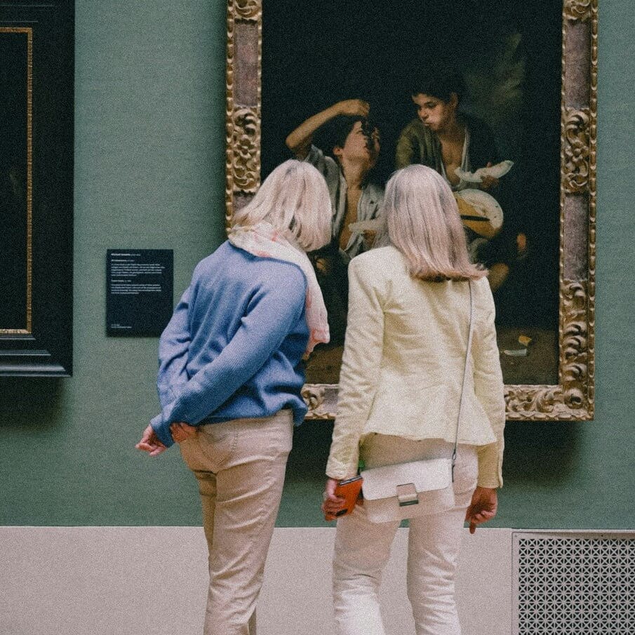 Two women looking at painting in a museum