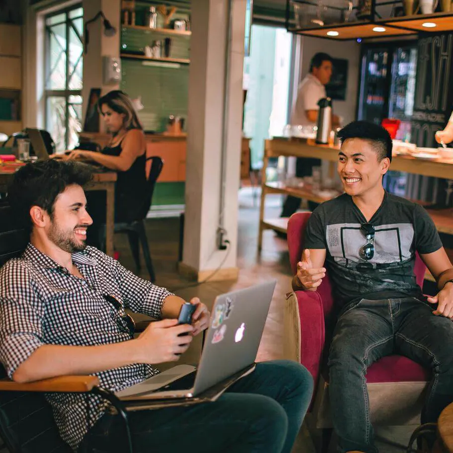 Two men sitting and laughing while working