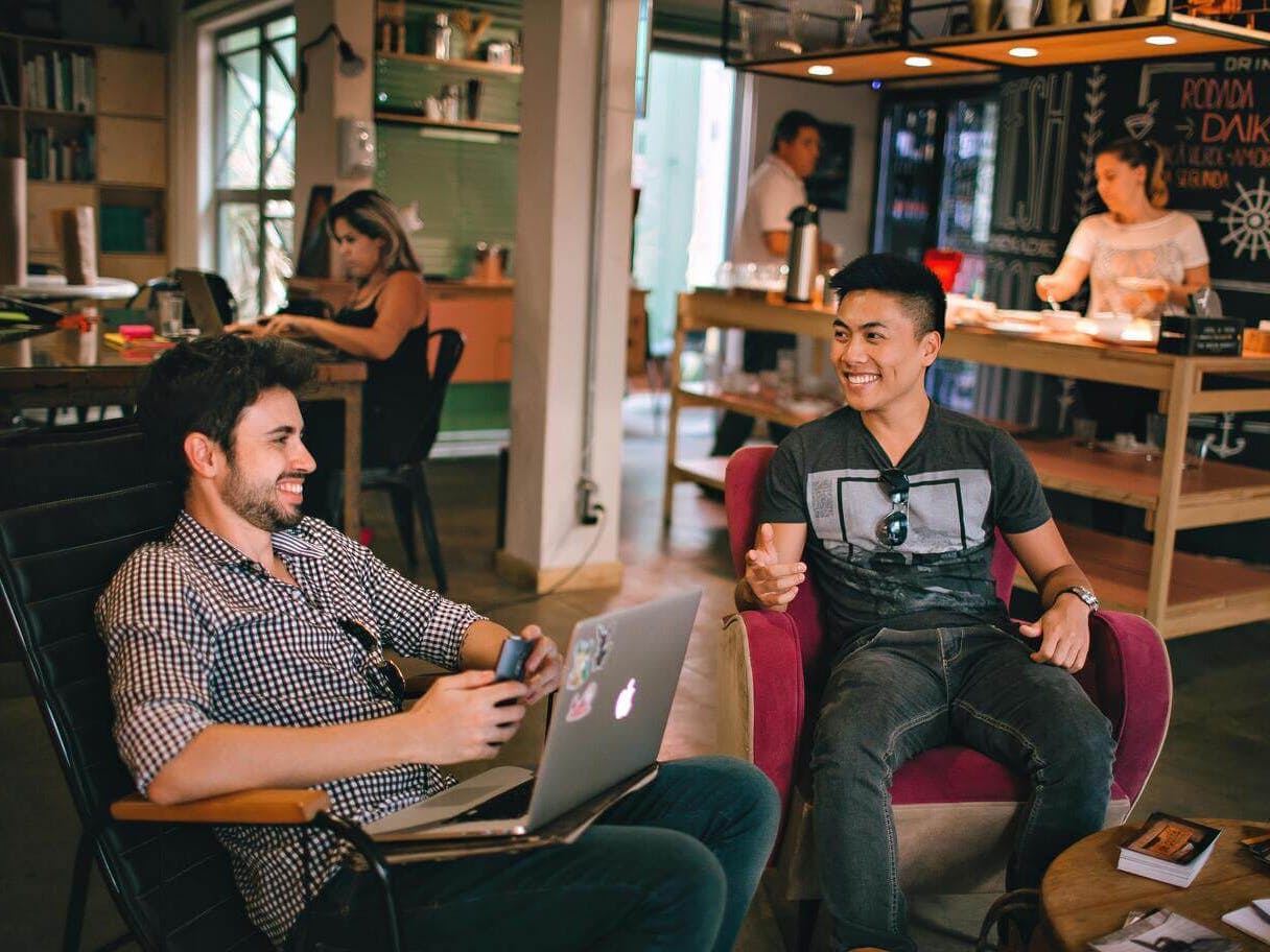 Two men sitting and laughing while working