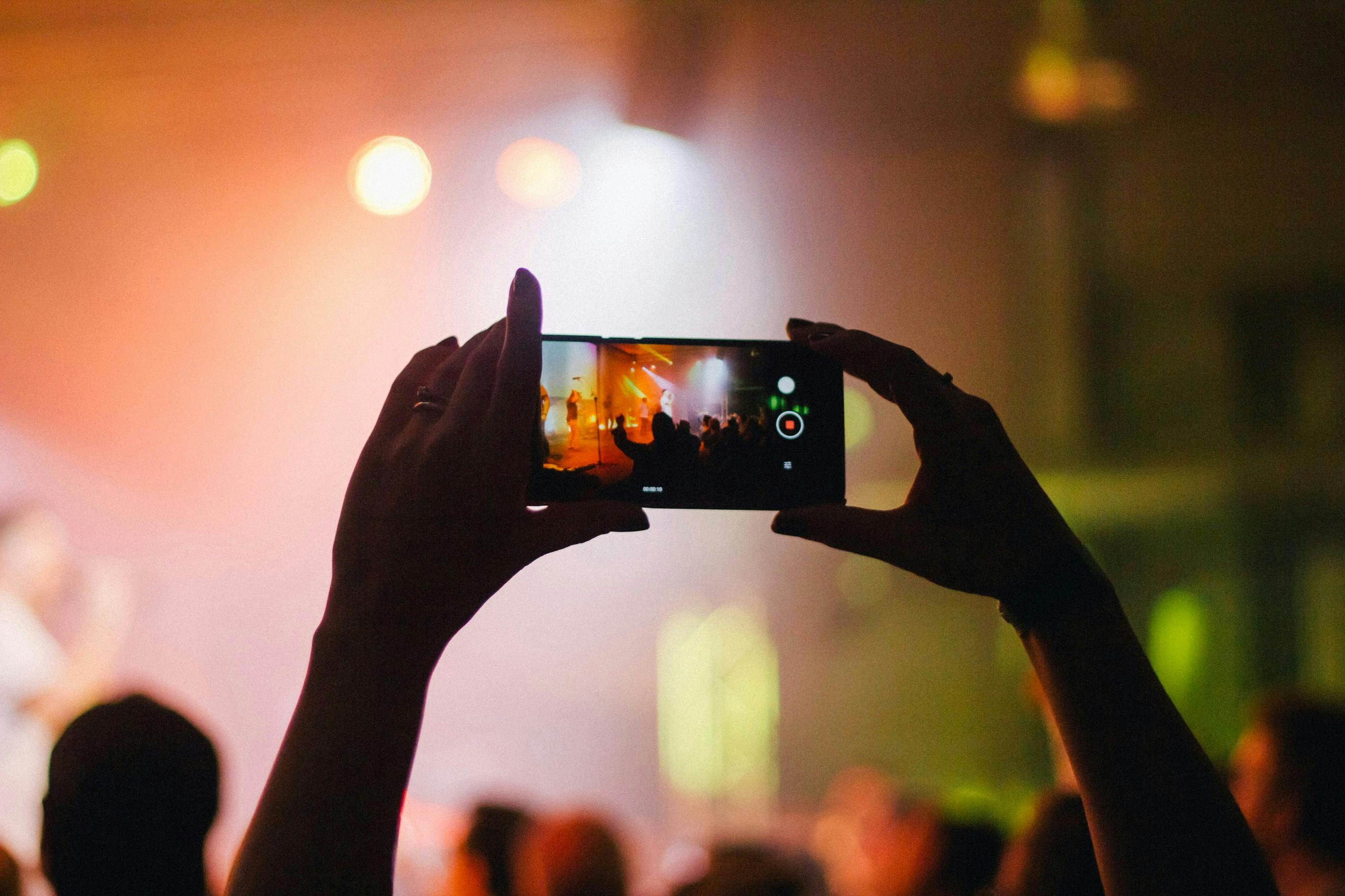 Person holding up phone to film concert