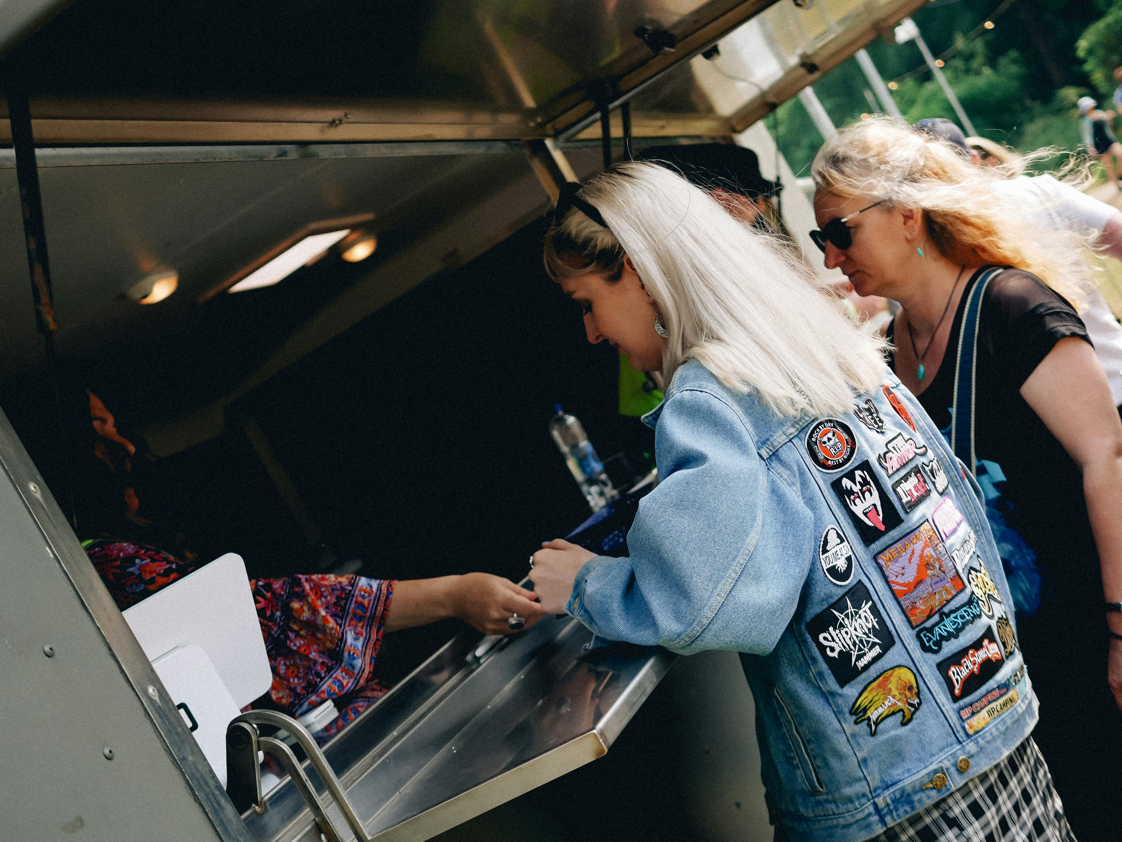The Great Estate Festival two people ordering from a food truck with a funky denim jacket and loads of punk badges