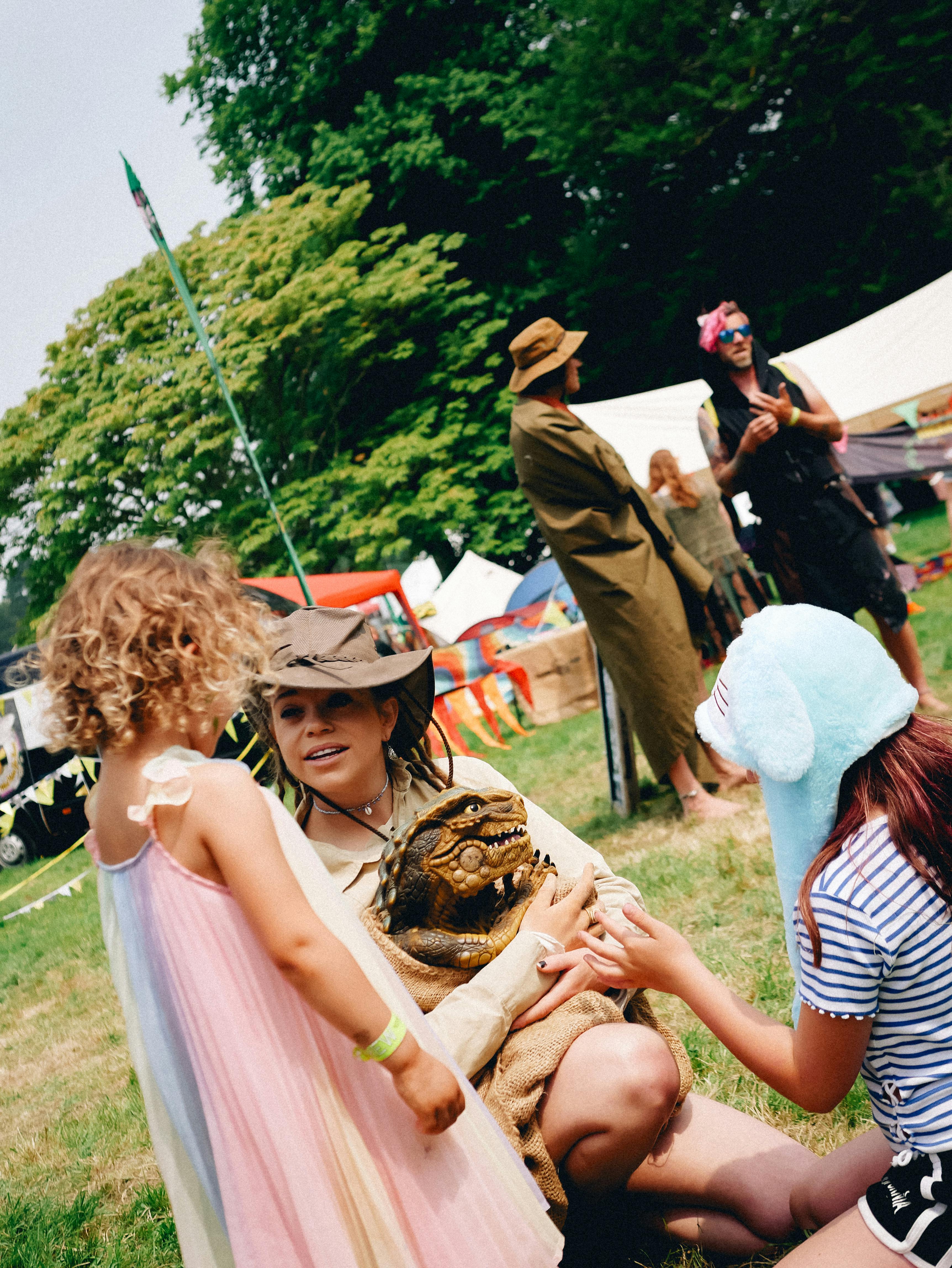 The Great Estate Festival lady with dinosaur puppet and two children interacting with her