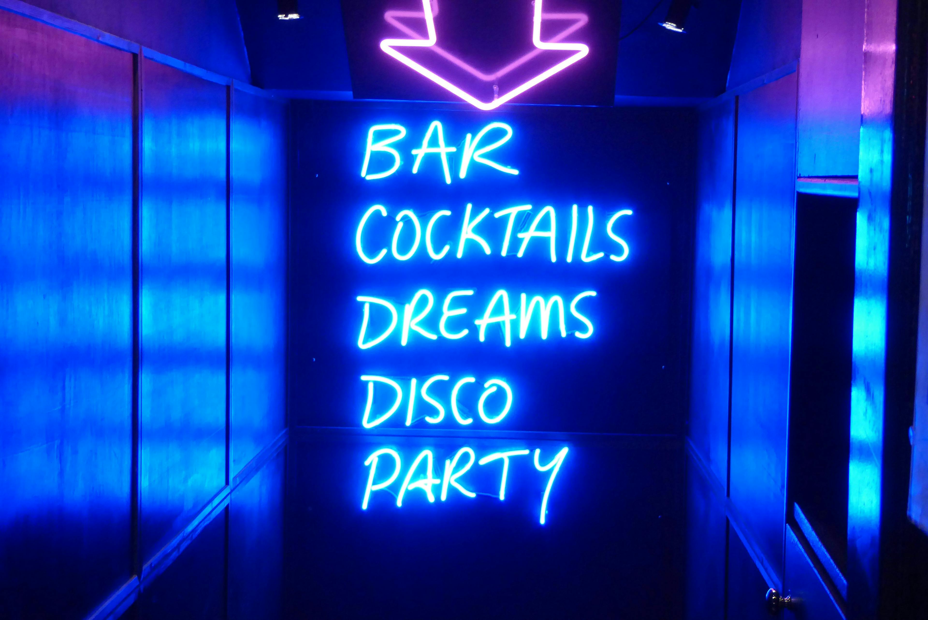 Neon nightclub sign reading Bar, Cocktails, Dreams, Disco, Party