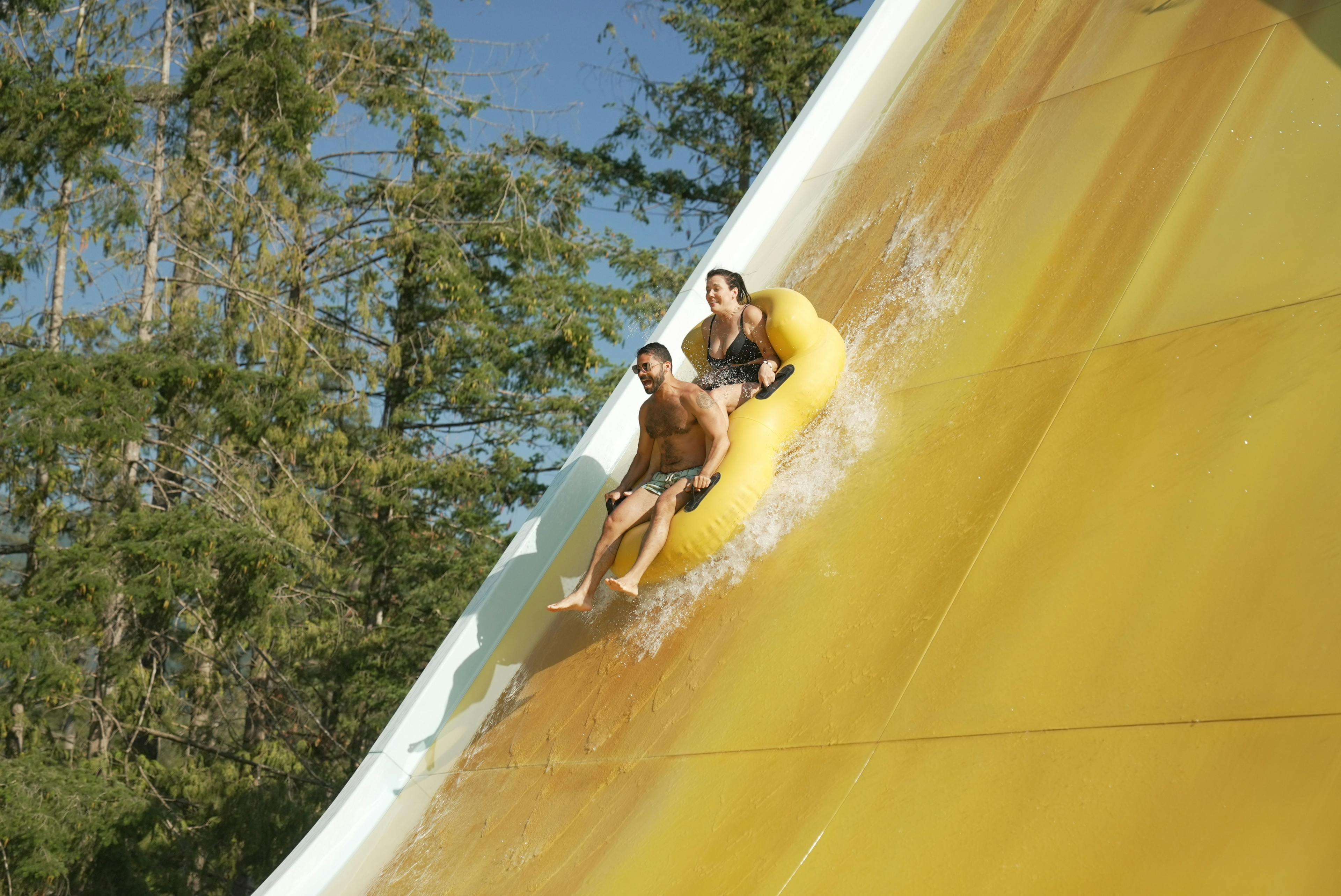 People in rubber ring on steep yellow slide
