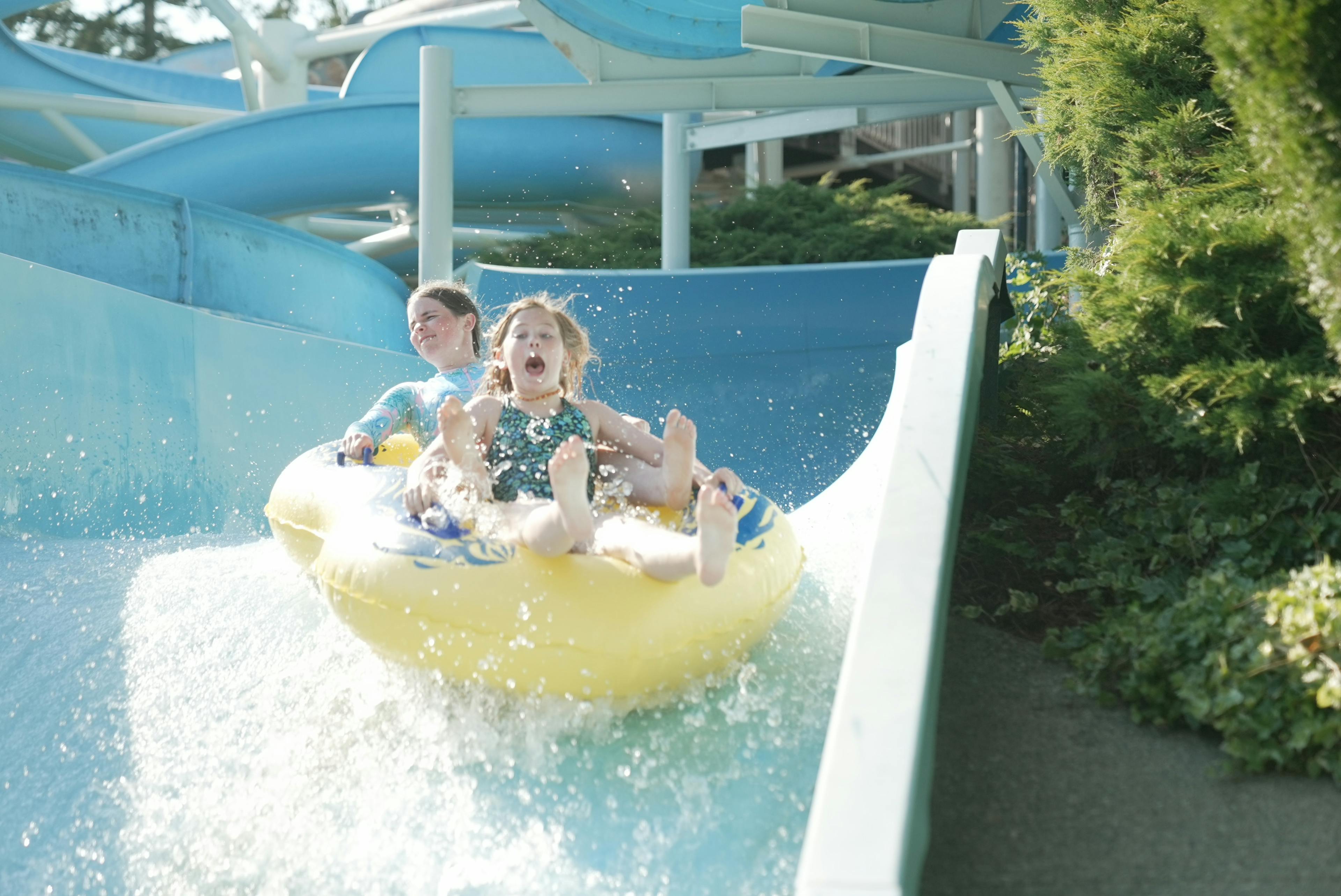 Cultus Lake Waterpark two people in rubber ring on blue slide screaming and water splashing