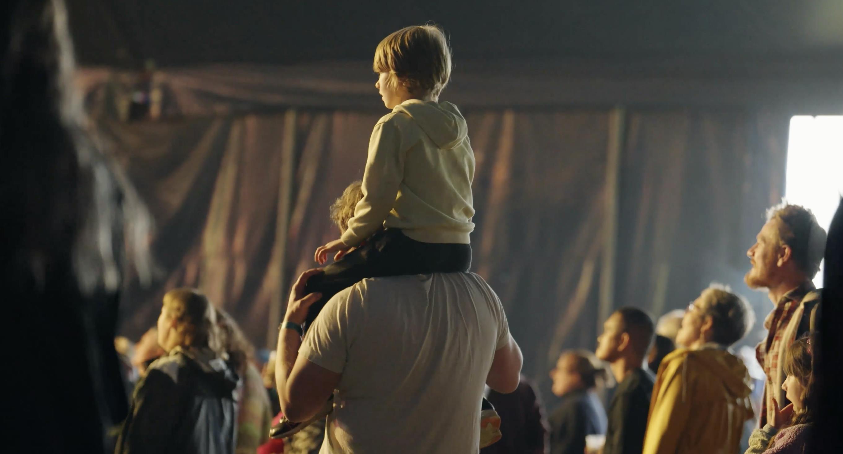 child on shoulders in crowd