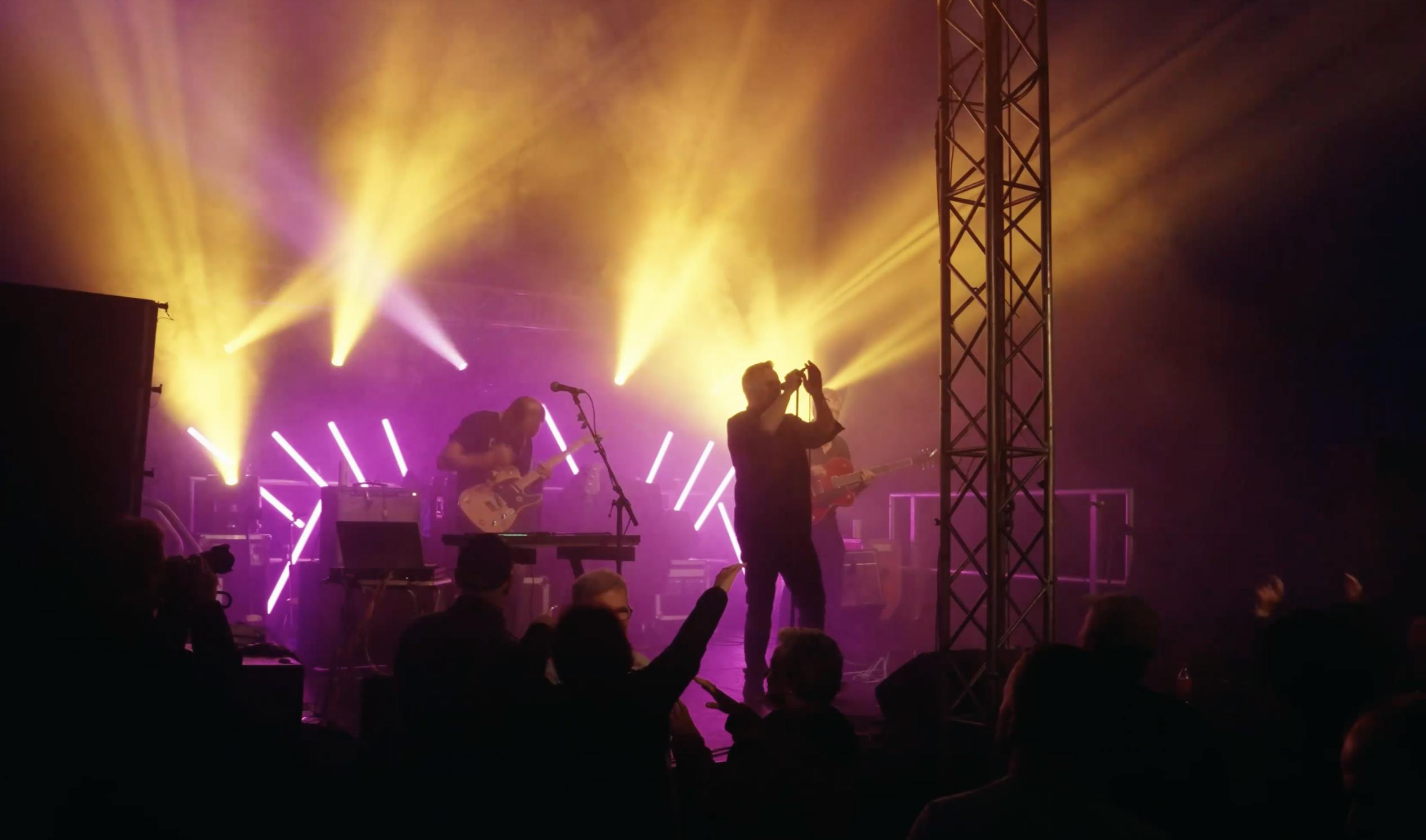 person on stage singing with yellow and purple lights