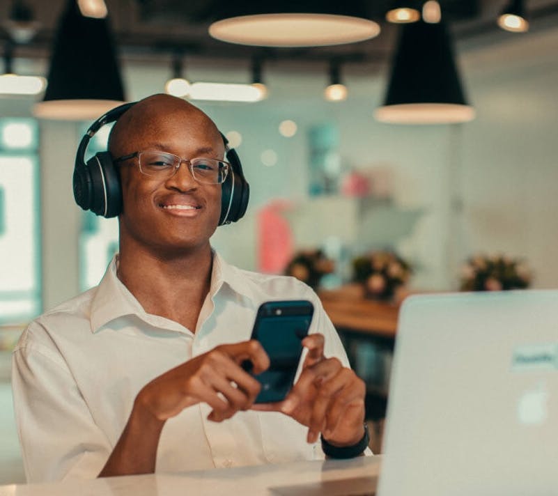 Man working on phone and computer with headphones on