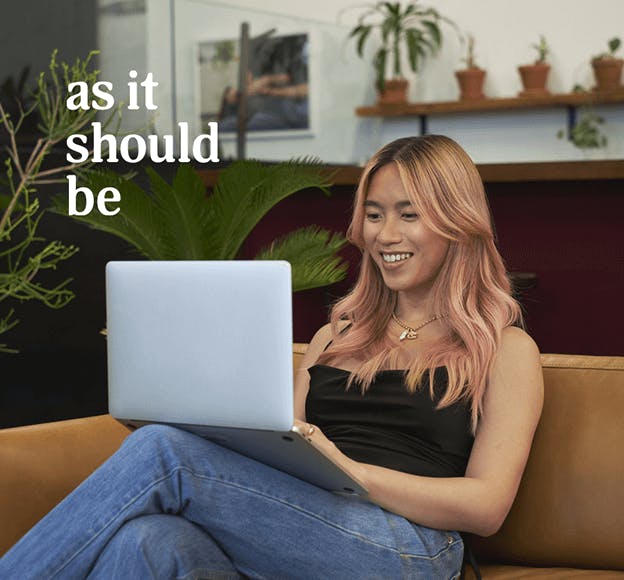 A transfeminine person smiling and using a laptop