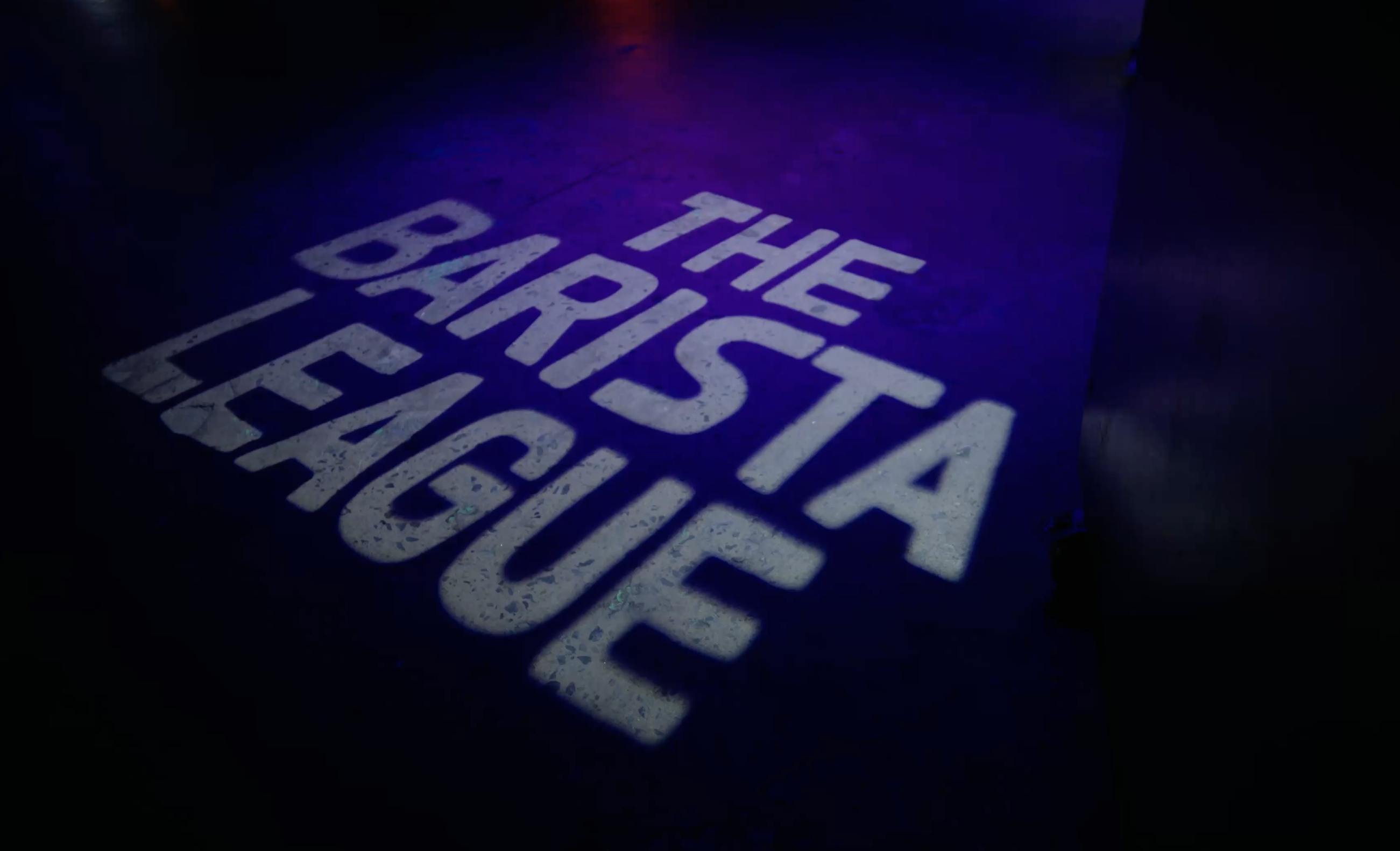 The Barista League logo lit on floor