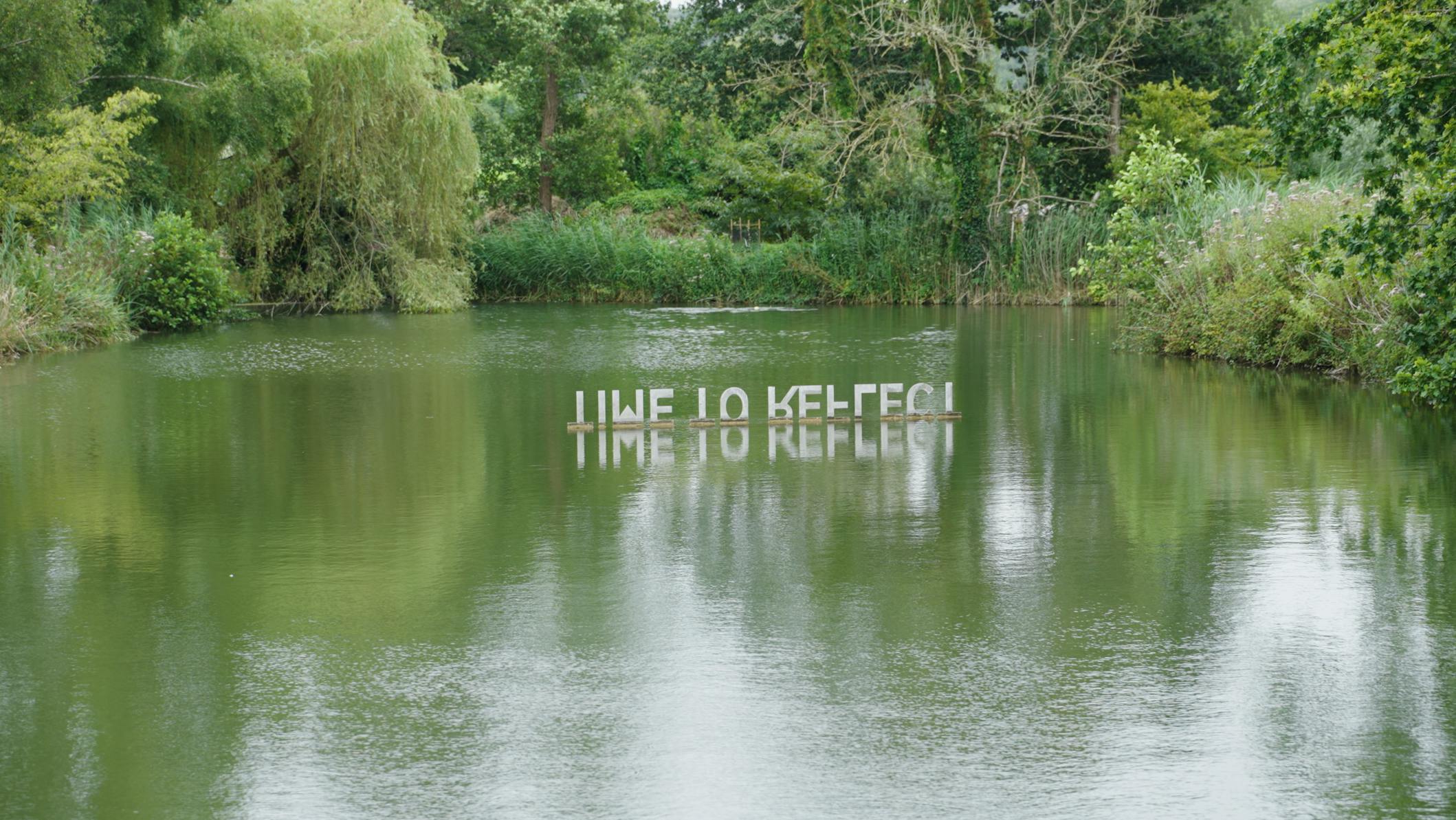 Sculpture by the Lakes - sculpture of letters that is reflected in water and reads 'Time to Reflect'