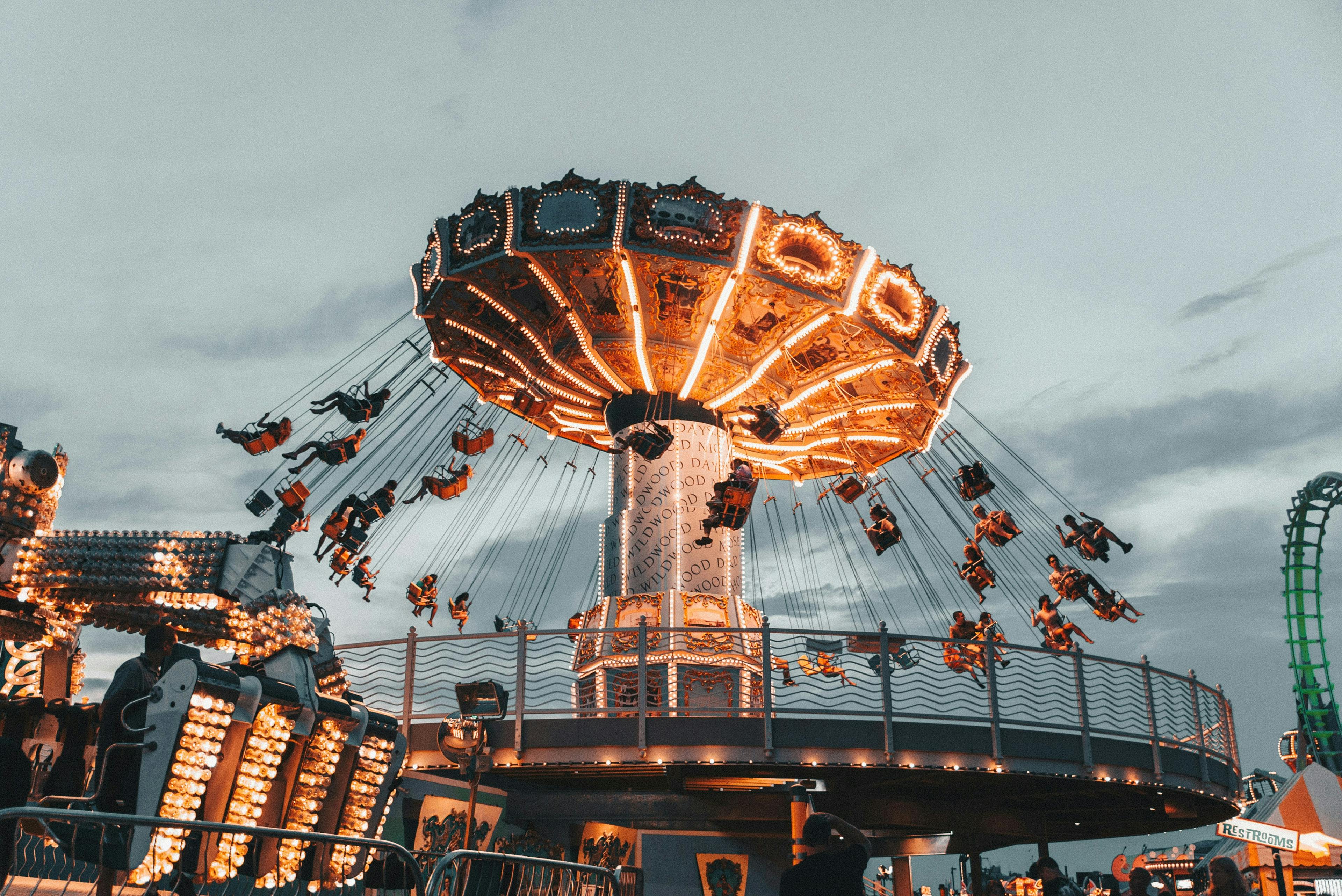 Carousel swing ride lit up against evening sky at a theme park