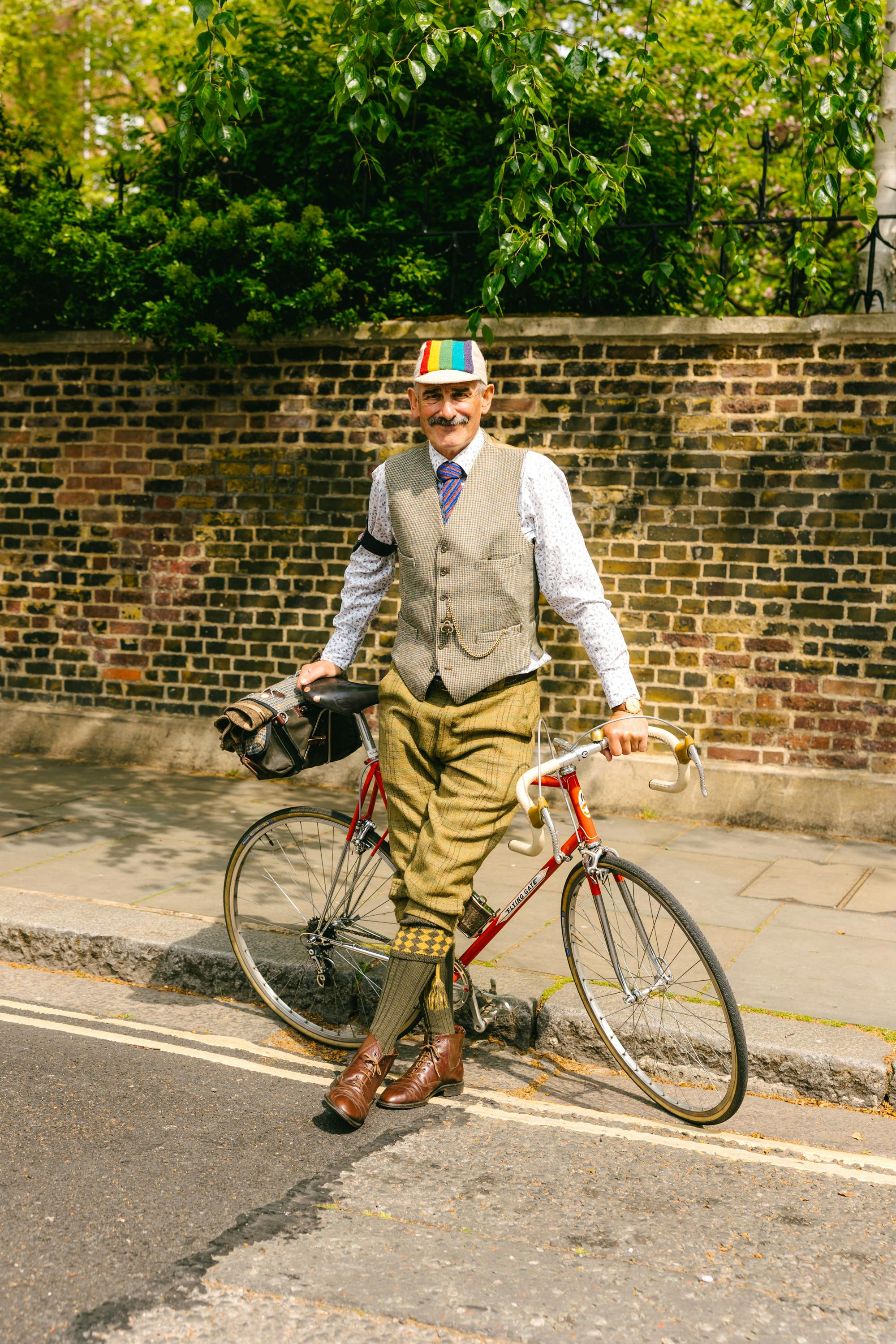 The Tweed Run dapper man leaning on bike with legs crossed