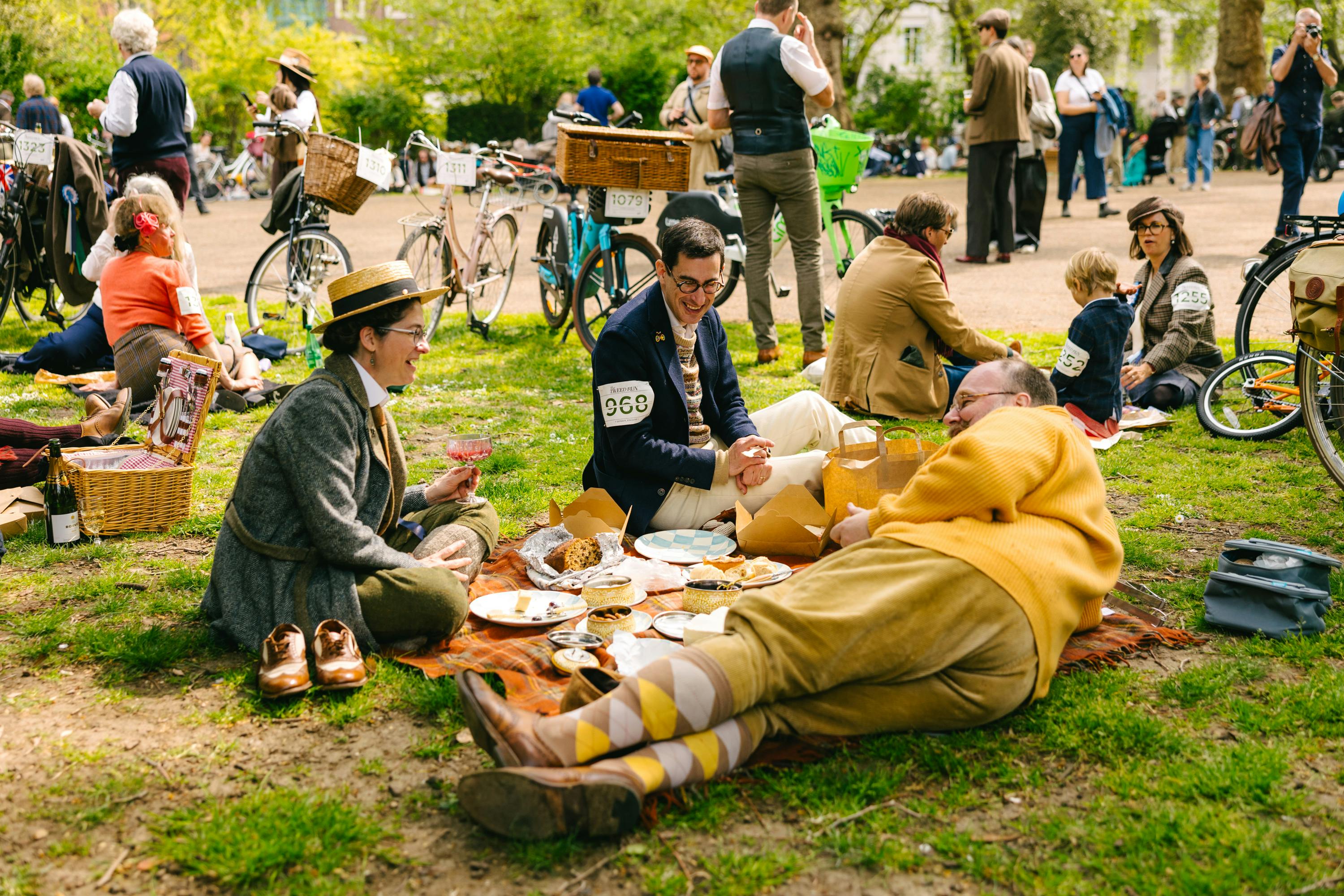 The Tweed Run group lying around picnic blanket with bikes