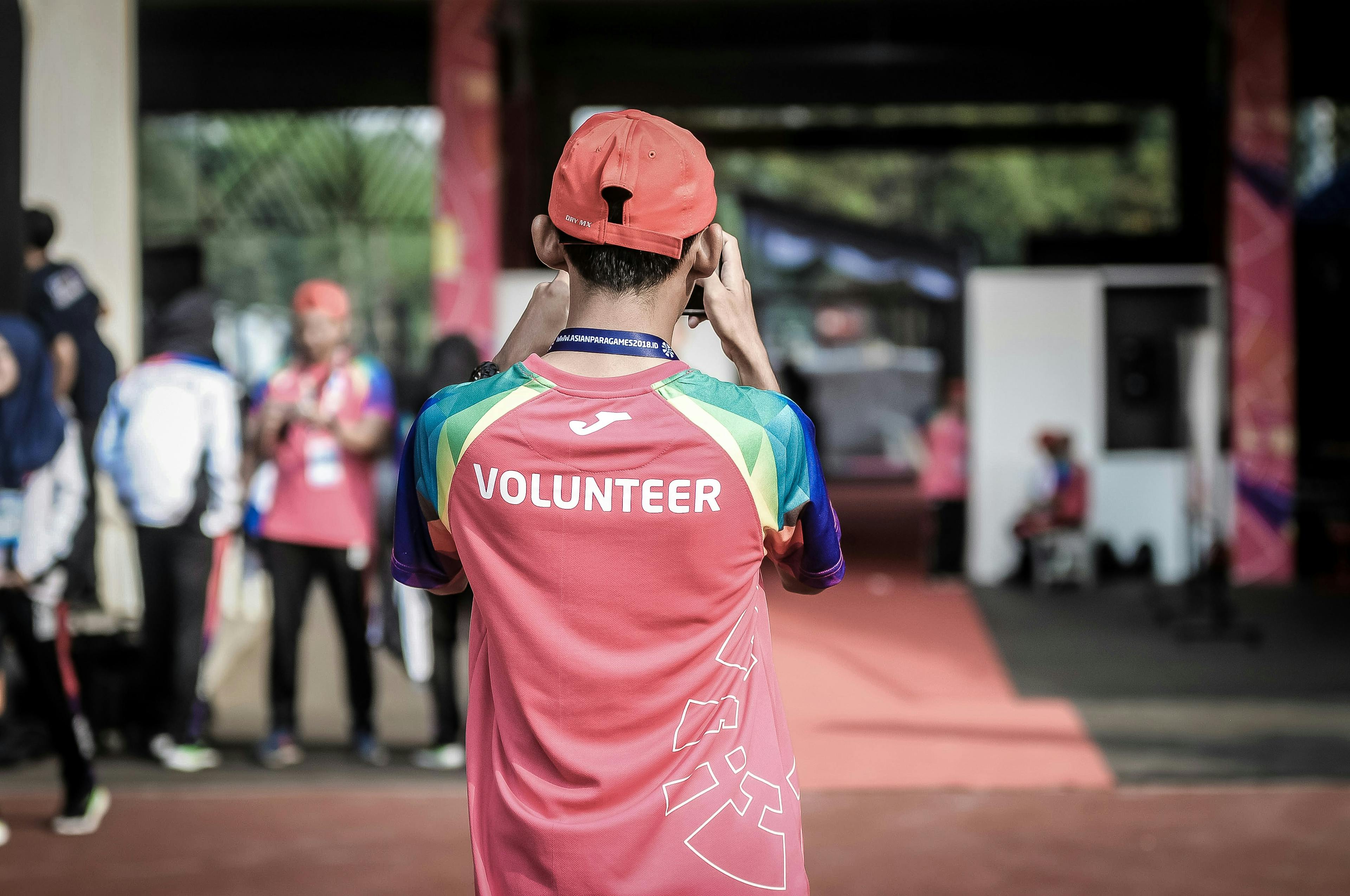Image of man wearing a red volunteer photo taken from behind