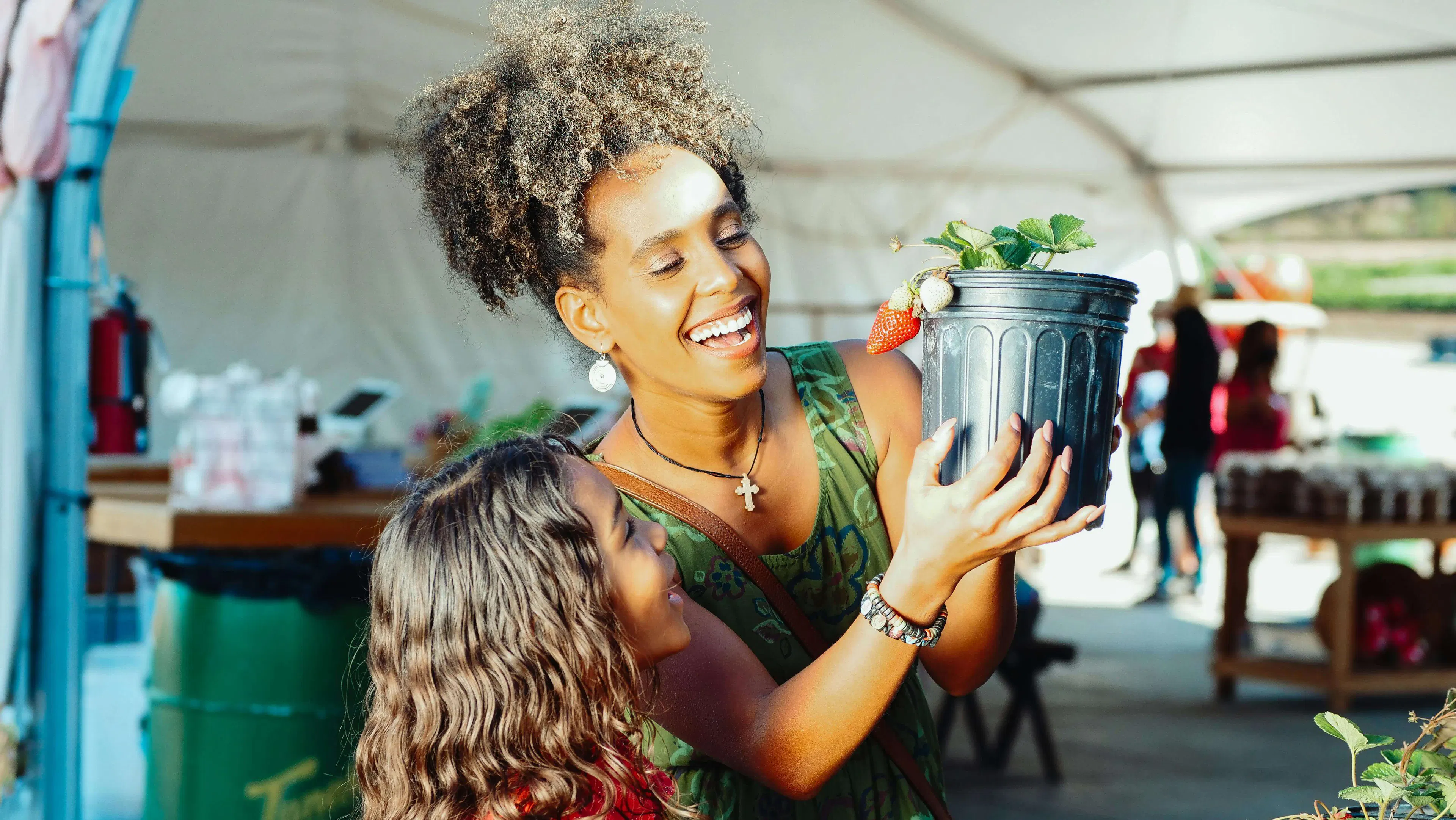mother and child picking strawberries and smiling
